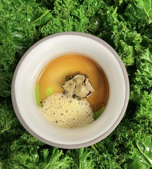 Suppe in einem Teller mit Salat im Hintergrund